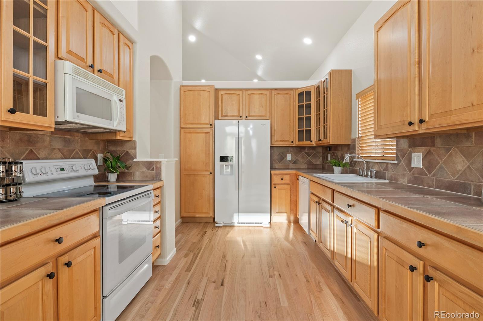 6900 West Grant Ranch Boulevard, Unit 53 Littleton, CO 80123 - Photo 13 of 31 a kitchen with stainless steel appliances granite countertop a refrigerator a sink dishwasher a stove and white countertops with wooden floor