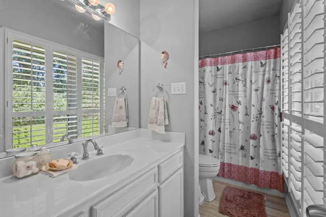 a bathroom with a granite countertop sink a toilet a shower and a mirror