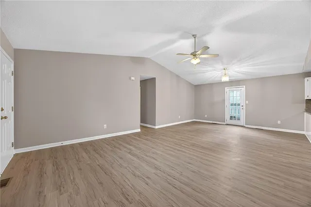 a view of an empty room with window and wooden floor