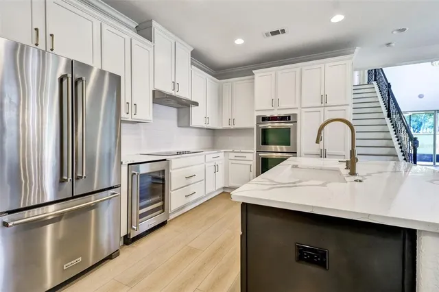 a kitchen with granite countertop a sink stainless steel appliances and white cabinets