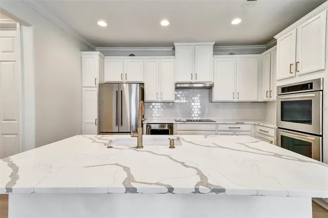 a kitchen with stainless steel appliances kitchen island granite countertop a refrigerator oven a sink with cabinets and wooden floor