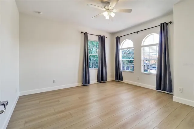 a view of an empty room with a window and wooden floor