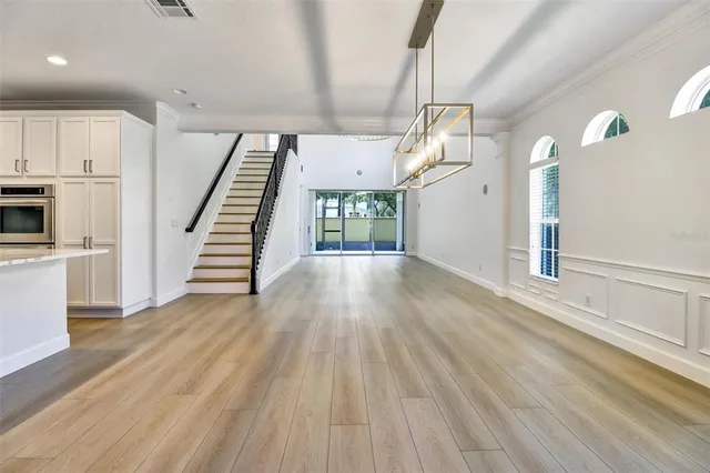 an empty room with wooden floor staircase and windows