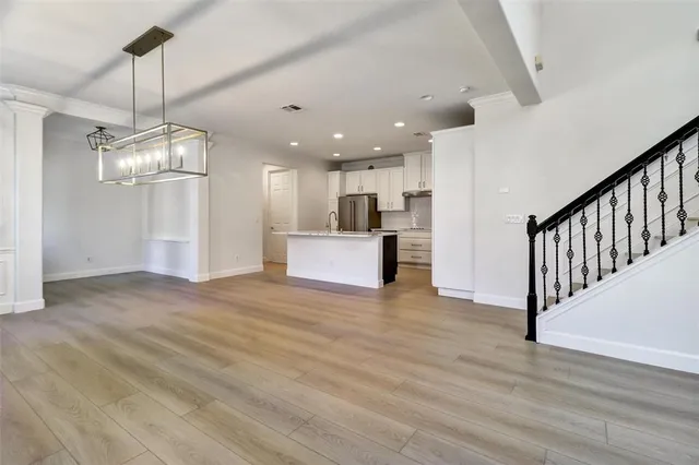 a view of a kitchen with a refrigerator wooden floor and a chandelier