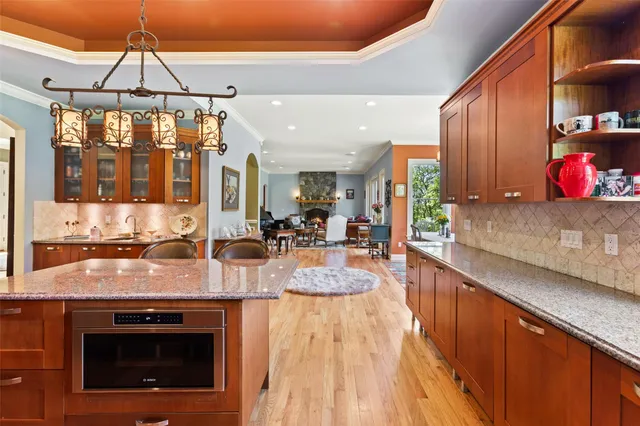 a view of a kitchen with kitchen island granite countertop a stove and a wooden floors