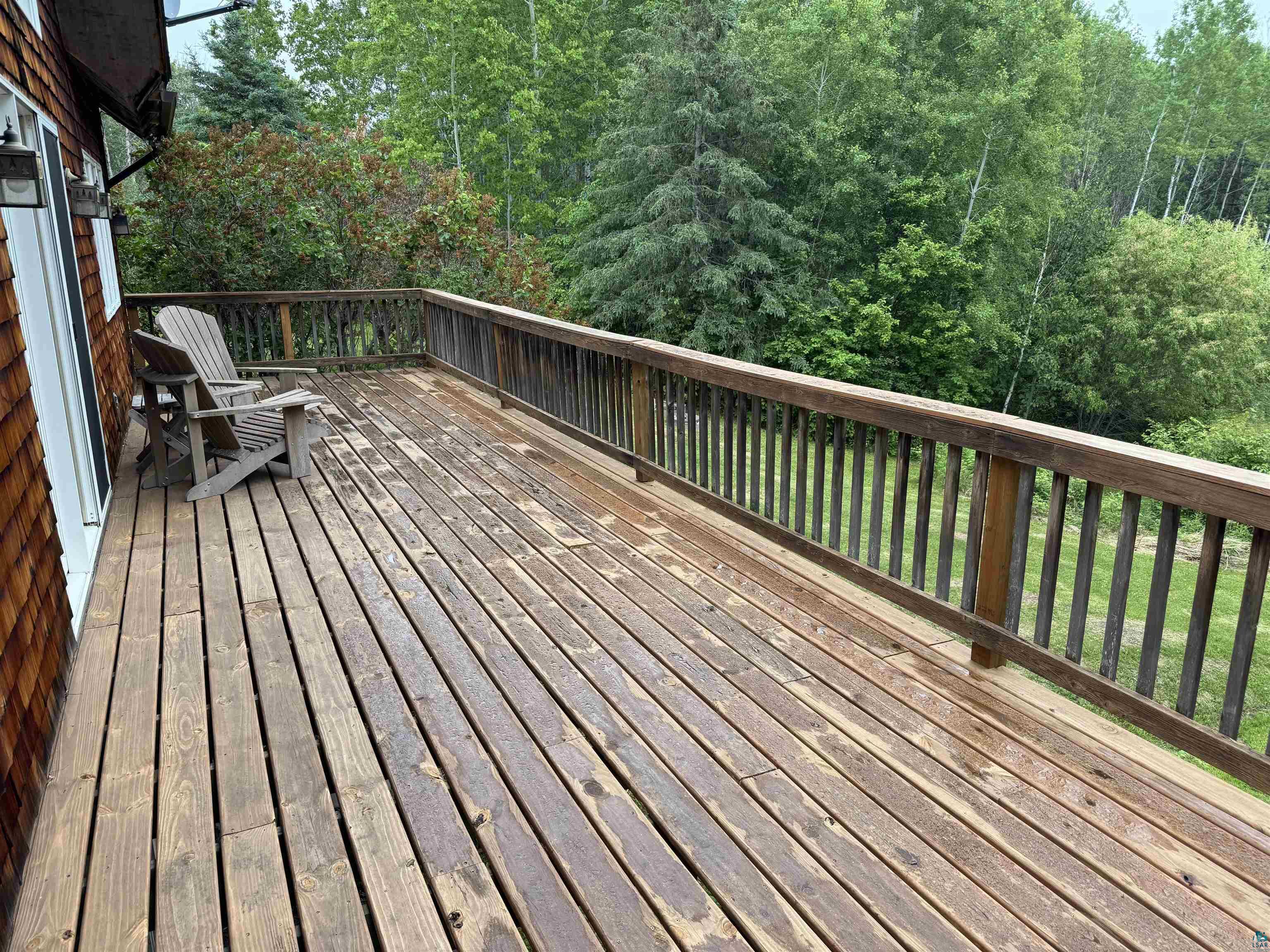 1745 Becks Road Maple, WI 54854 - Photo 33 of 46 Expansive wood deck with a full-length wood railing, offering a natural backdrop, overlooking back yard with an intermittent creek.