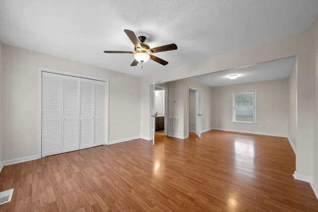 a view of an empty room with window and wooden floor