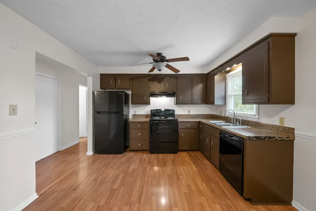 a kitchen with granite countertop a refrigerator stove top oven and sink