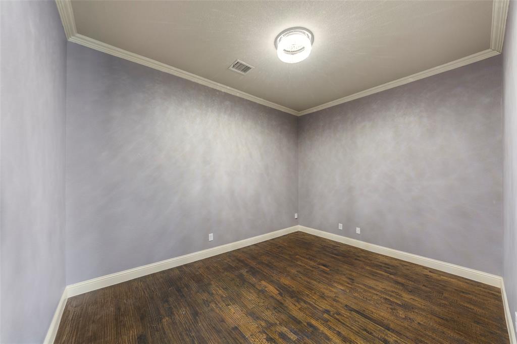 7929 Maddox Road Plano, TX 75024 - Photo 13 of 26 1st level room with molding and dark wood-style flooring. This space can be a sleep space, workout, office or gaming room. Full bath & laundry on first level as well.