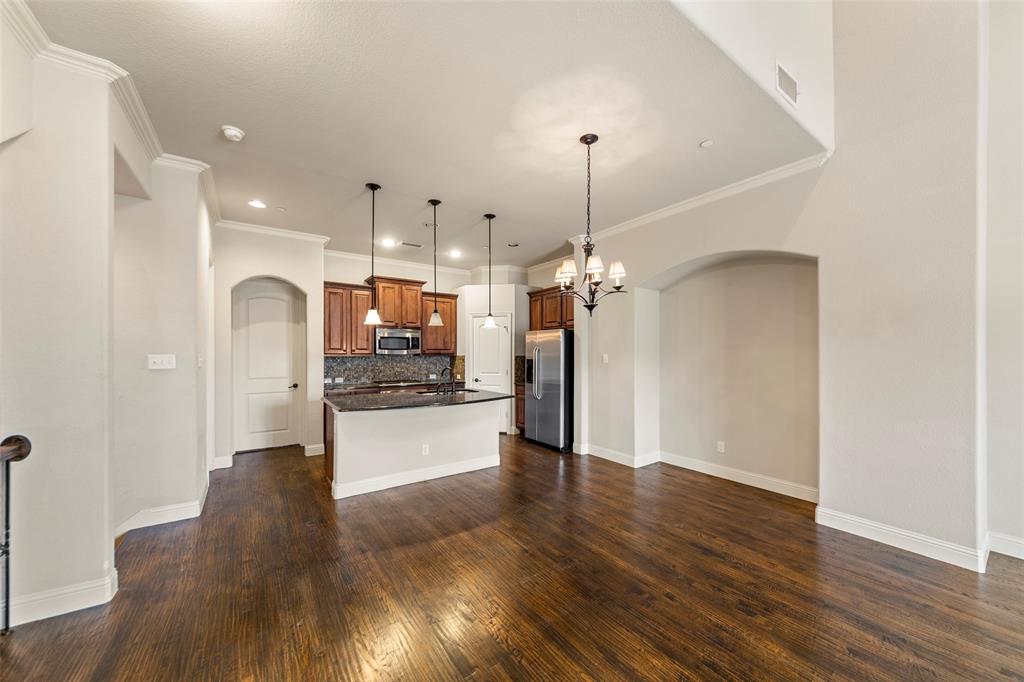 7929 Maddox Road Plano, TX 75024 - Photo 25 of 26 Kitchen with arched walkways, a kitchen island with breakfast bar and sink, open floor plan, crown molding, and stainless steel appliances.