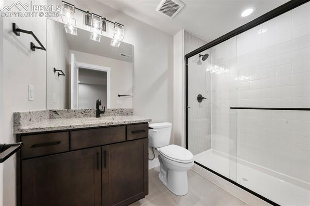 11762 Rambling Road Colorado Springs, CO 80908 - Photo 41 of 42 Bathroom with tile flooring, vanity, toilet, and a shower with shower door