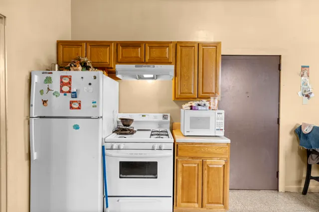 a white refrigerator freezer and a stove sitting inside of a kitchen