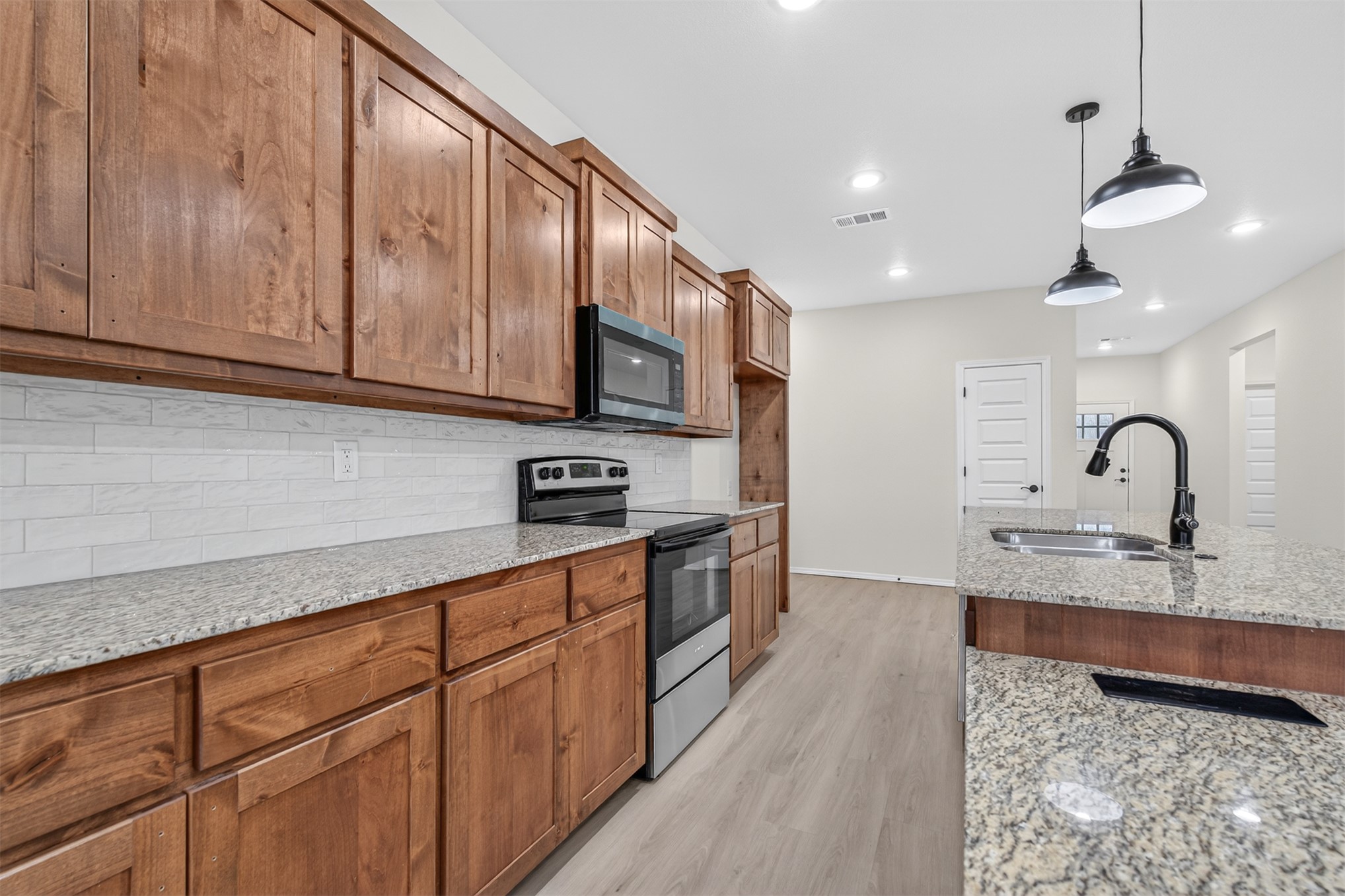 124 Countryside Way Pocola, OK 74902 - Photo 22 of 39 Spacious kitchen featuring wood cabinetry, light-toned granite countertops, a subway tile backsplash, and stainless steel appliances