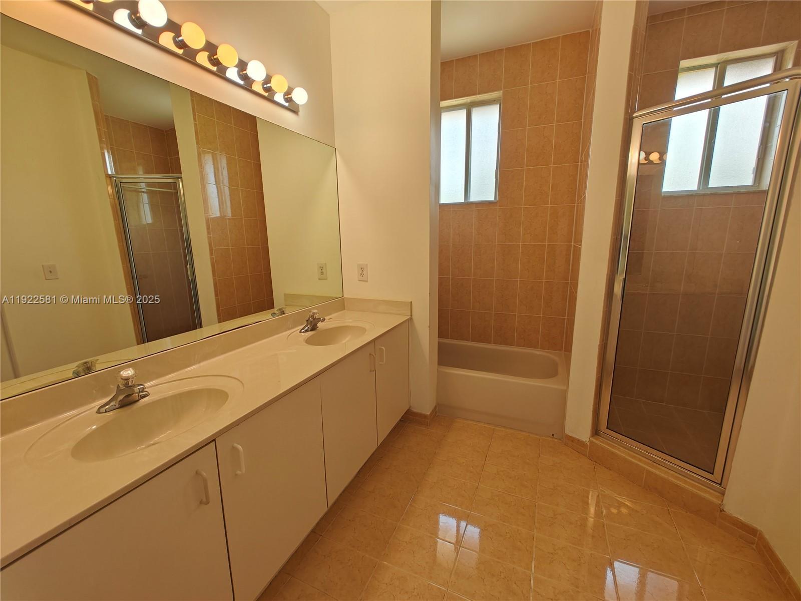 11252 Southwest 230th Terrace, Unit 11252 Miami, FL 33170 - Photo 14 of 28 a bathroom with a double vanity sink a mirror and a bathtub