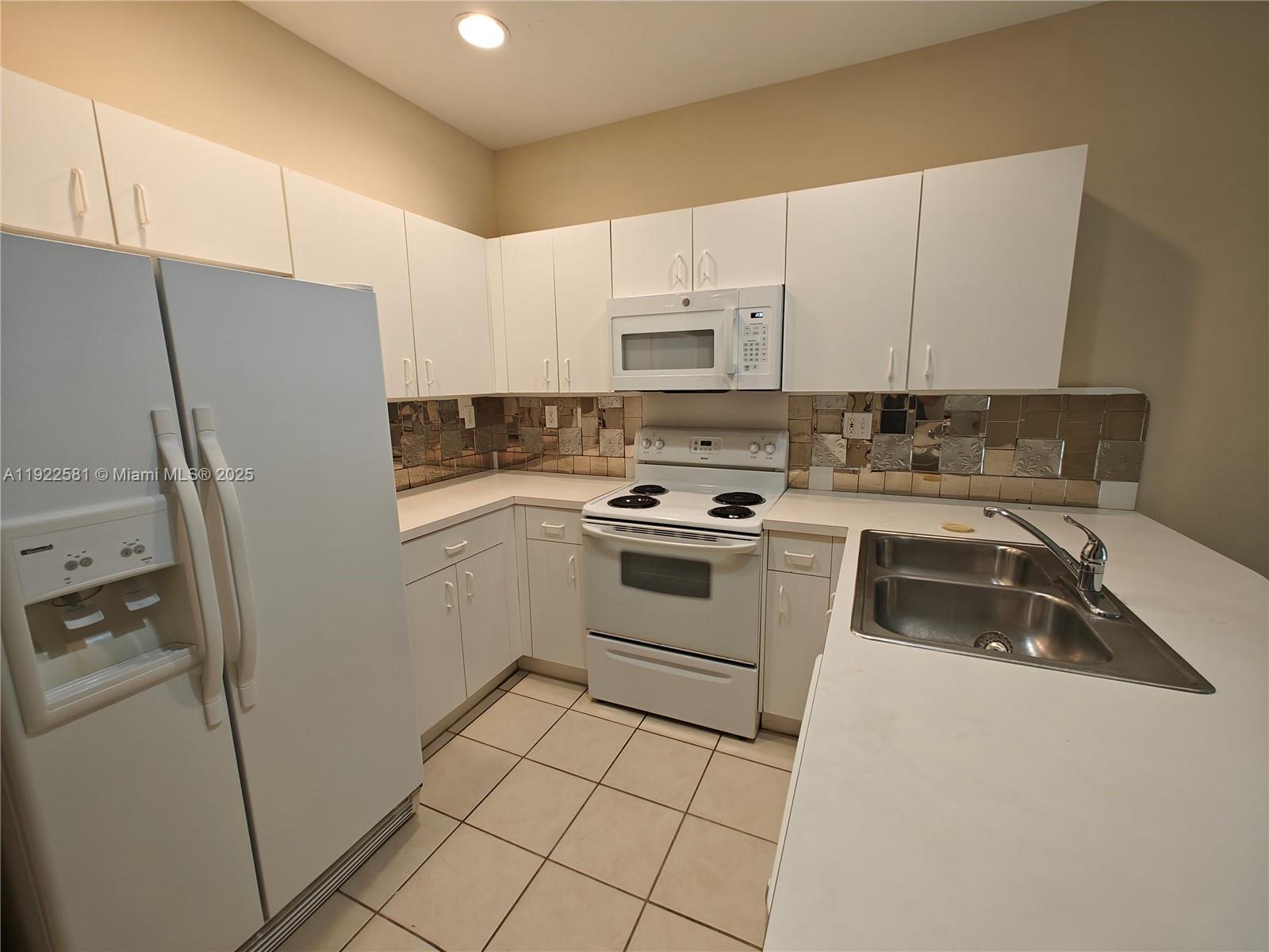 11252 Southwest 230th Terrace, Unit 11252 Miami, FL 33170 - Photo 7 of 28 a kitchen with a refrigerator sink and cabinets