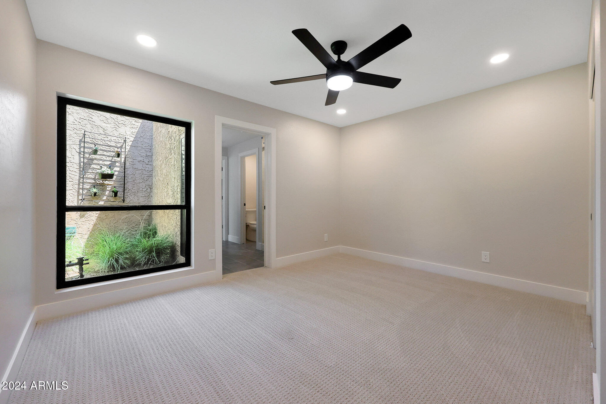 4440 East Camelback Road, Unit 32 Phoenix, AZ 85018 - Photo 36 of 54 an empty room with large windows and a ceiling fan
