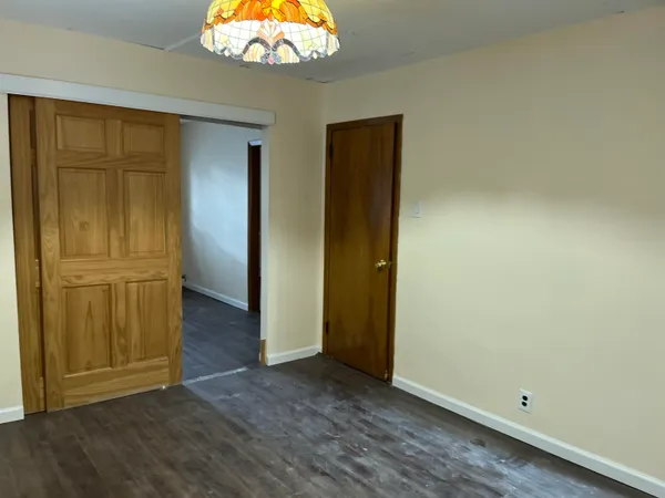 an empty room with wooden floor cabinet and windows