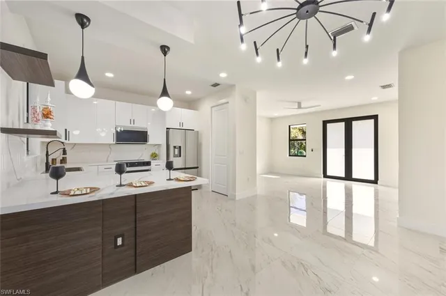 a open kitchen with stainless steel appliances granite countertop a refrigerator a sink dishwasher a oven and a dining table with wooden floor