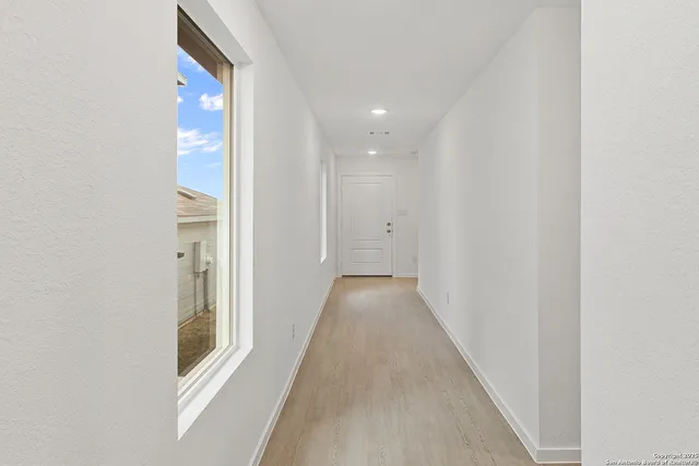 a view of a hallway with wooden floor and a bathroom
