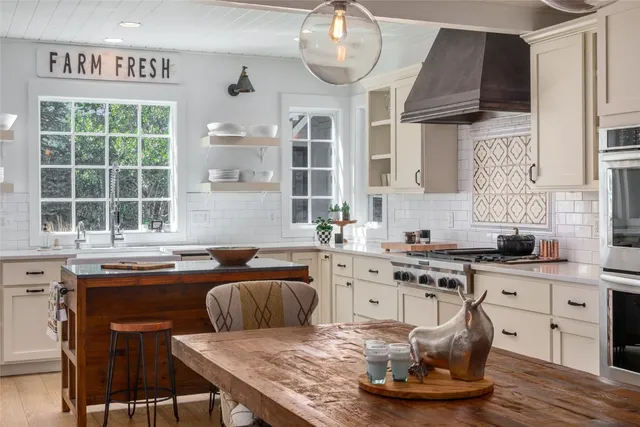 a kitchen with a stove a sink dishwasher a dining table and chairs with wooden floor