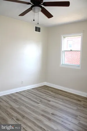 an empty room with wooden floor ceiling fan and windows