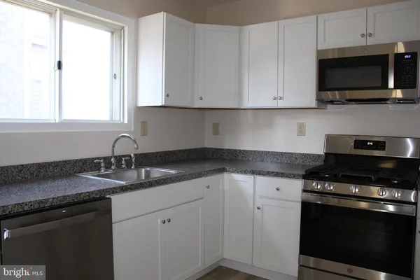 a kitchen with granite countertop white cabinets and black appliances