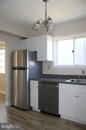 a kitchen with stainless steel appliances granite countertop a refrigerator a sink dishwasher a stove and white cabinets