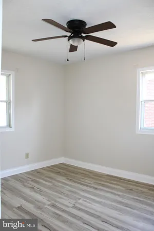 a view of a room with wooden floor a ceiling fan and window