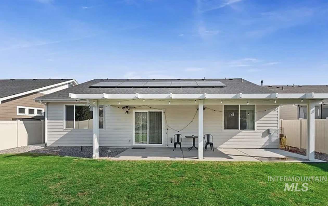 5773 West Riva Capri Street Meridian, ID 83646 - Photo 4 of 4 Back of property featuring a fenced backyard, a patio area, solar panels, and a shingled roof