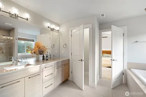 a spacious bathroom with a double vanity sink a large mirror and a bathtub