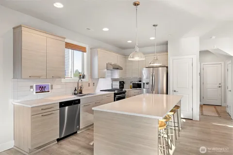 a large kitchen with kitchen island a large counter space stainless steel appliances a sink and a window