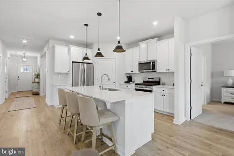 a kitchen with stainless steel appliances granite countertop a sink a stove and a wooden floors