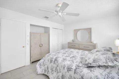 a bedroom with a large bed and a chandelier fan