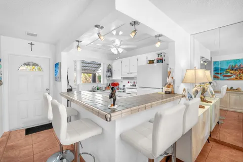 a very nice looking dining room with kitchen island a chandelier