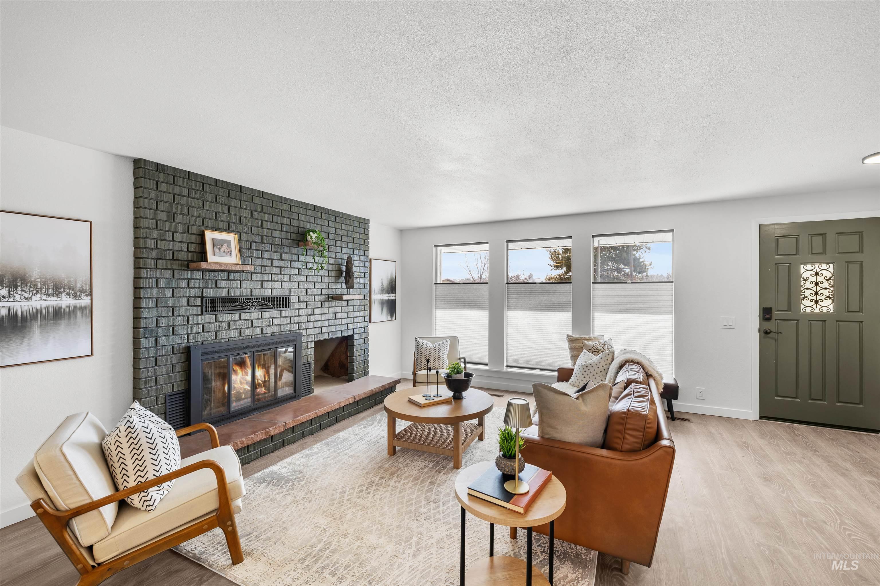 7144 West Diamond Street Boise, ID 83709 - Photo 6 of 47 Living area with a brick fireplace, wood finished floors, and a textured ceiling