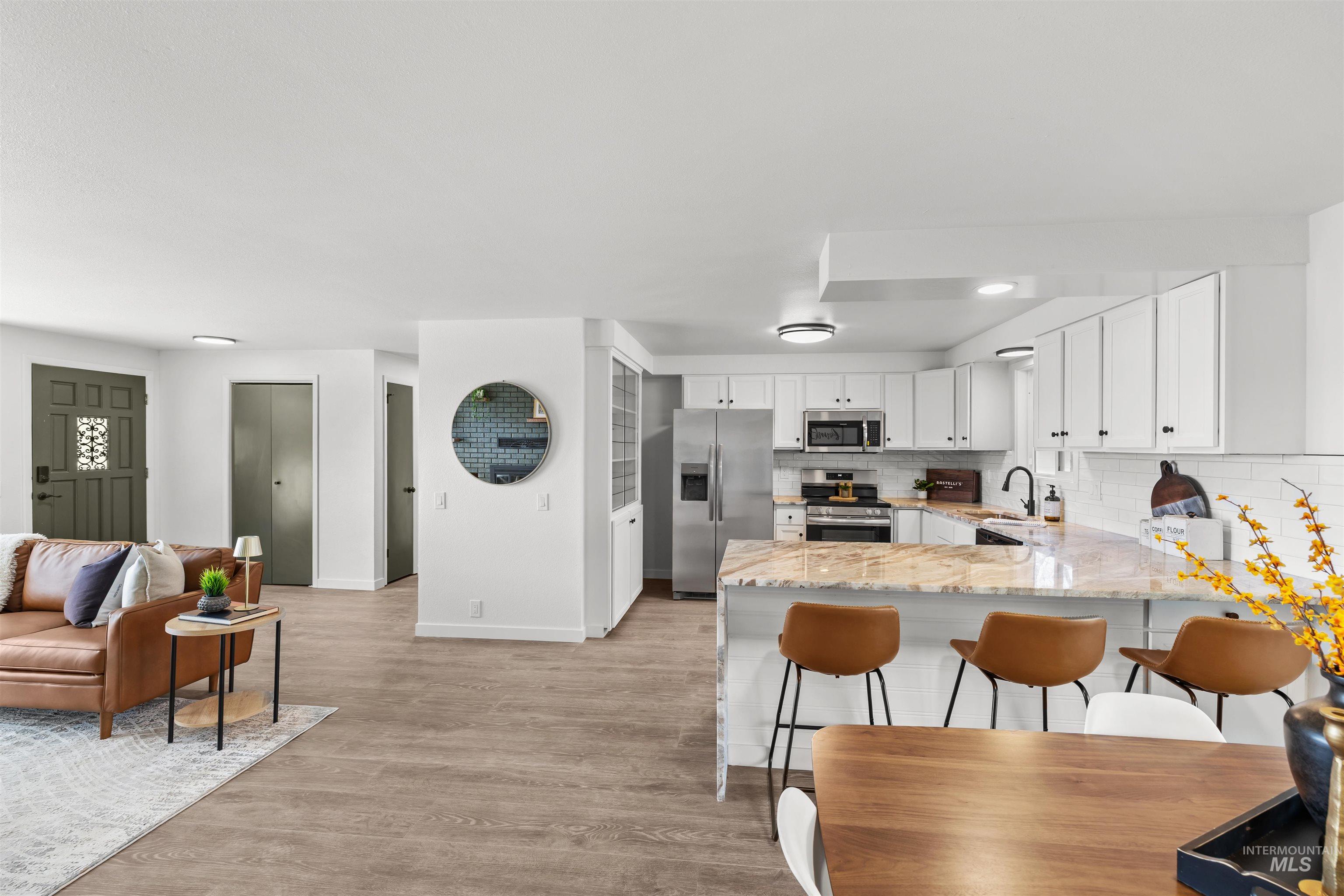 7144 West Diamond Street Boise, ID 83709 - Photo 8 of 47 Kitchen featuring light stone countertops, stainless steel appliances, a peninsula, white cabinetry, and light wood-style floors