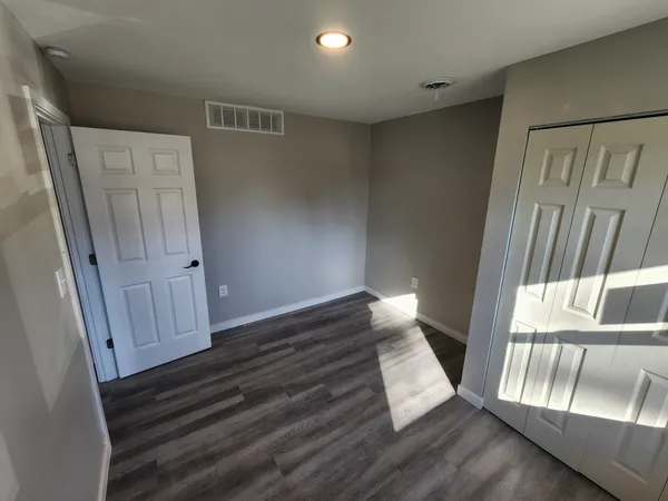 a view of an empty room with wooden floor and stairs