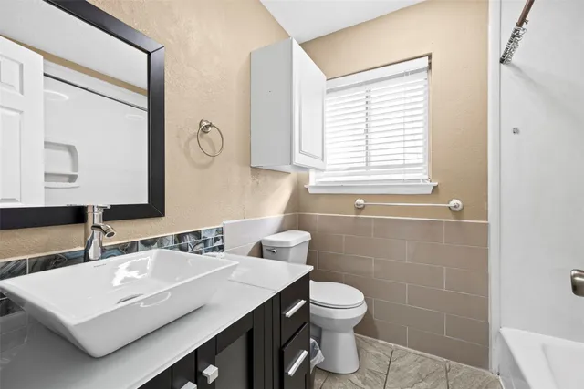 a bathroom with a sink vanity granite toilet and a mirror