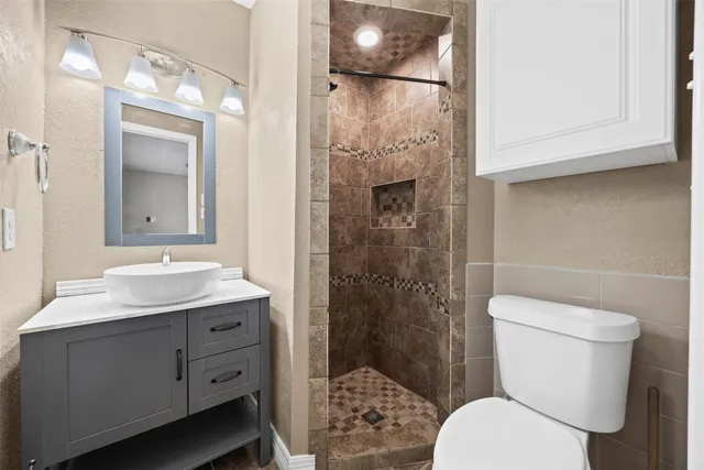 a bathroom with a granite countertop toilet a sink and a mirror