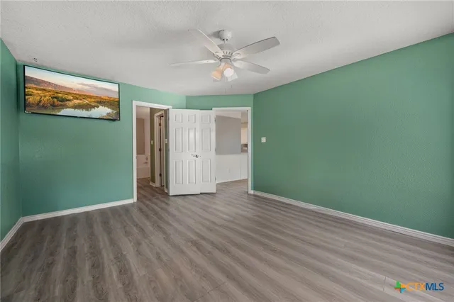 a view of a livingroom with wooden floor and a ceiling fan