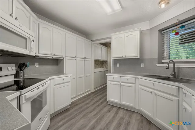 a kitchen with granite countertop white cabinets and white appliances