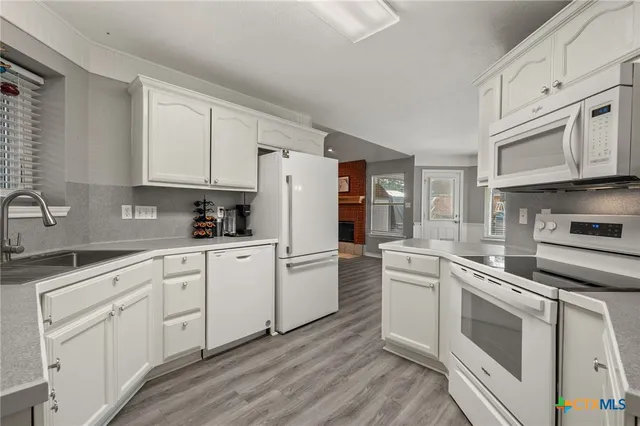 a kitchen with granite countertop white cabinets and white appliances