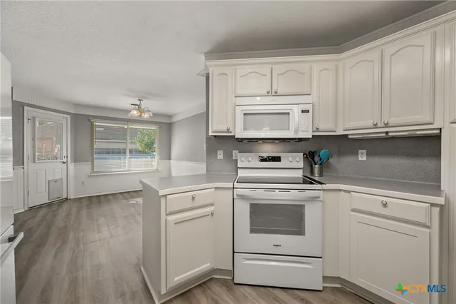 a kitchen with granite countertop white cabinets and white appliances