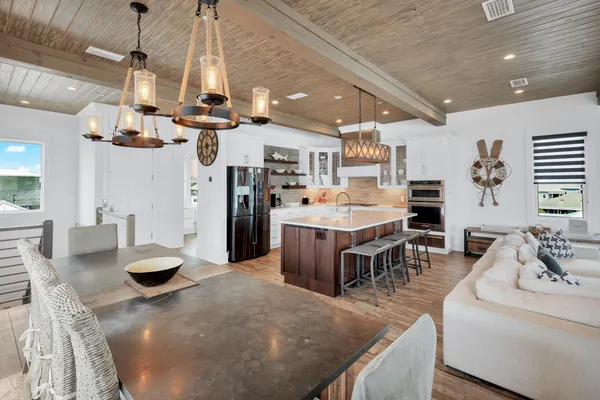 a kitchen with stainless steel appliances kitchen island granite countertop a stove a oven a dining table and chairs with the kitchen view