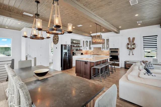 a kitchen with stainless steel appliances kitchen island granite countertop a stove a oven a dining table and chairs with the kitchen view