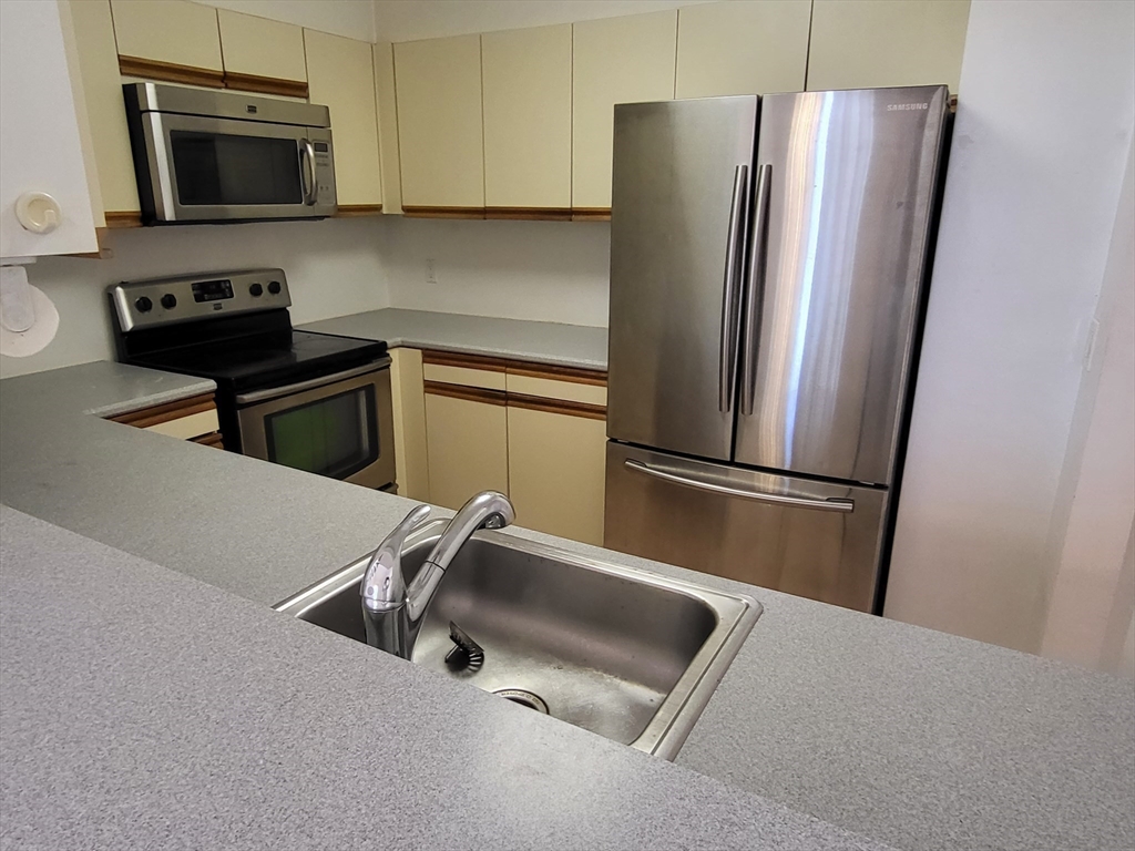 35 Walden Street, Unit 3B Cambridge, MA 02140 - Photo 9 of 39 a kitchen with stainless steel appliances a refrigerator sink and microwave