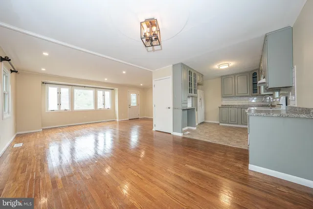 a view of a kitchen and an empty room with wooden floor and a window