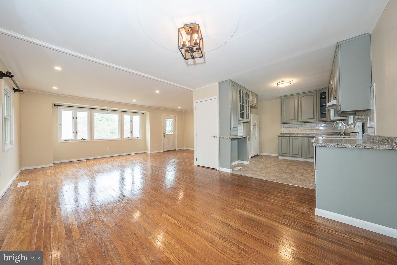 437 Meadowcroft Road Wayne, PA 19087 - Photo 3 of 19 a view of a kitchen and an empty room with wooden floor and a window