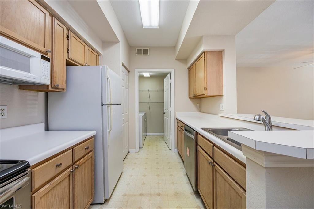 4635 St Croix Lane, Unit 1218 Naples, FL 34109 - Photo 10 of 40 Kitchen with light flooring, white appliances, light countertops, a peninsula, and independent washer and dryer