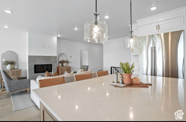 599 North Heritage Street, Unit 6 Mapleton, UT 84664 - Photo 11 of 37 Kitchen with light hardwood / wood-style floors, stainless steel fridge, pendant lighting, a fireplace, and white cabinets